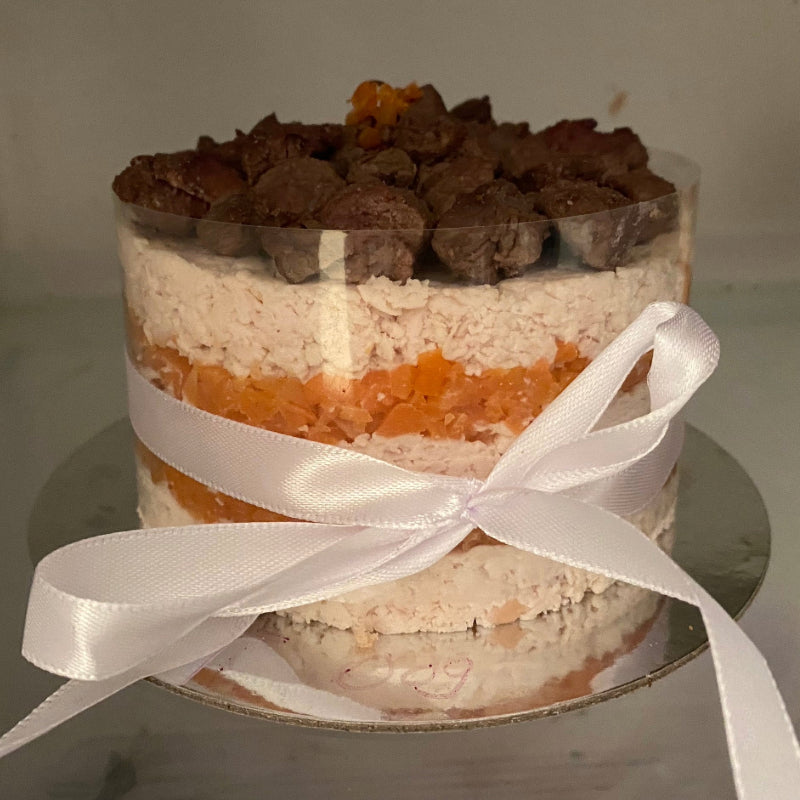 A meat cake made from layers of carrot and butter baked chicken breast, topped with braised beef and presented with a ribbon