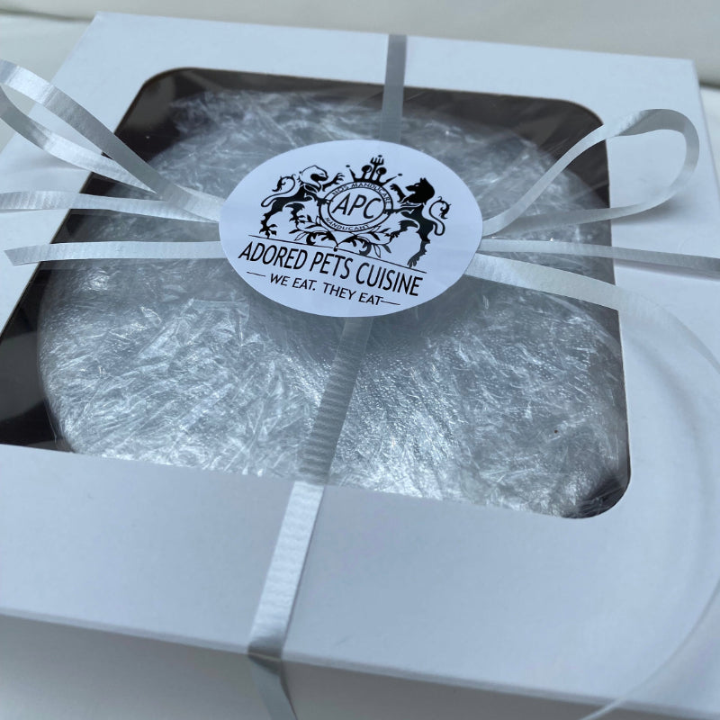 A boxed meat cake for dogs or cats, presented with a ribbon and an Adored Pets Cuisine sticker