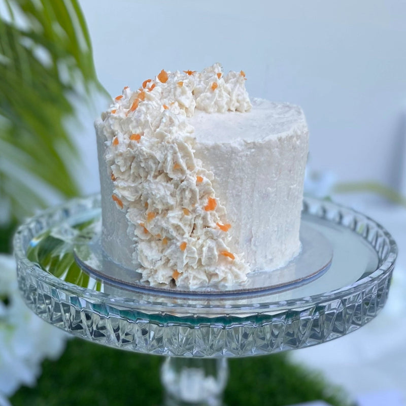 A chicken frosted meat cake for pets, garnished with chicken parfait swirls and fresh carrot, served on a glass serving platter