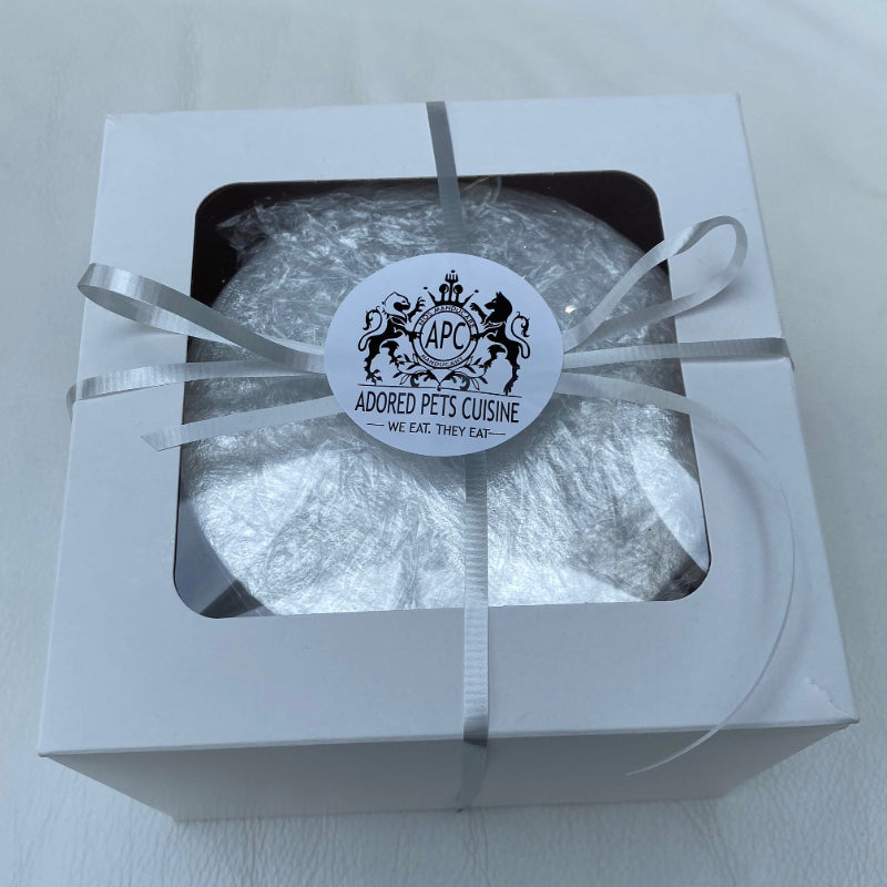 A boxed meat cake for dogs or cats, presented with a ribbon and an Adored Pets Cuisine sticker