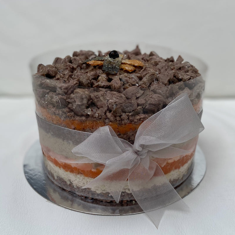 A large pet cake, made with layers of butter baked chicken breast and carrot, and wrapped with a ribbon.