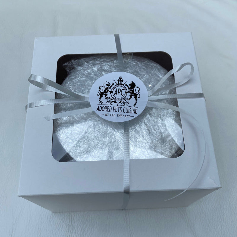 A boxed meat cake for dogs or cats, presented with a ribbon and an Adored Pets Cuisine sticker